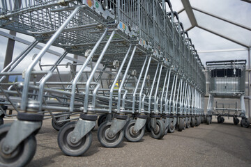 Shopping carts in a row. Round wheels and wire baskets. Deep perspective from the side.