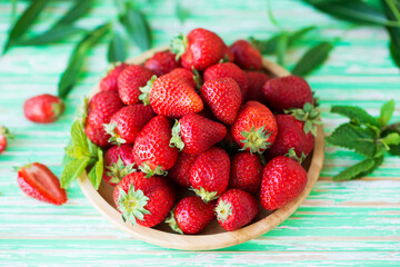 Fresh red strawberries in a plate on a rustic background, seasonal summer berries
