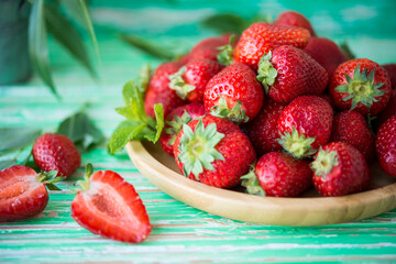 Fresh red strawberries in a plate on a rustic background, seasonal summer berries, selective focus