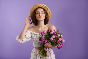 White young woman in hat making kiss lips while posing with tulips