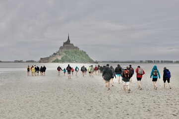 a large group of people walking toward mont saint michel in the bay at low tide