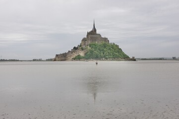 a guide is crossing mont saint michel bay at low tide