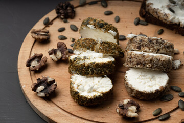 cheese cut into wedges next to walnuts on a wooden cutting board