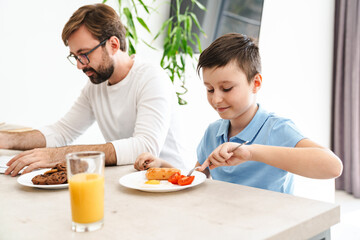 Obraz na płótnie Canvas Happy father and his son having breakfast