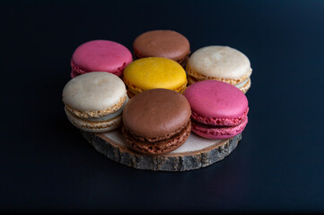 Macarons cookie dessert from France arranged on a wooden board as a flower, black background