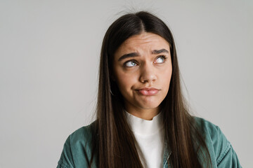 Fototapeta premium Young confused woman frowning and looking upward