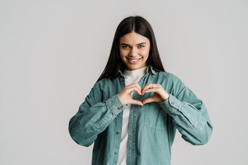 Young brunette woman smiling while showing heart gesture