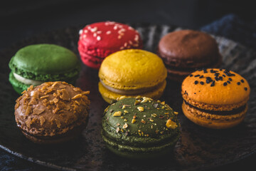 Colorful french macarons on a black plate, close up