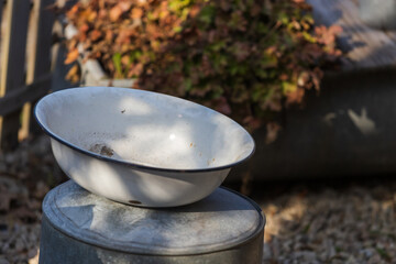 An old white water container stands on a tin barrel.
