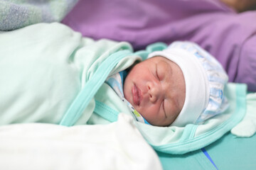 One-day-old newborn : A newborn baby lies in a baby bed after just giving birth in a hospital delivery room. selective focus.