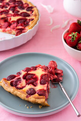 Table with a pink tablecloth, a bouquet of peonies and a sweet strawberry pie, pieces of pie on plates, a delicious summer dessert