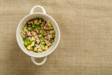 Okroshka in a tureen on a gray linen tablecloth.