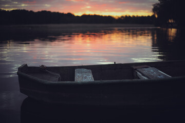 Pink sunset on the lake with an old boat. Blurred natural background, Sunset sky over lake