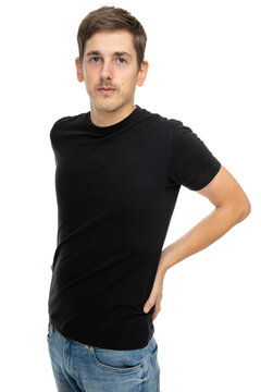 Young Handsome Tall Slim White Man With Brown Hair Touching His Back In Black Shirt In Blue Jeans Isolated On White Background