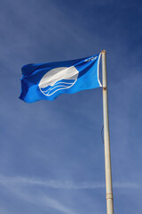 Blue flag of the year 2018. International symbol that identifies Beaches and Clean Ports and the trail of two planes crossing through the sky