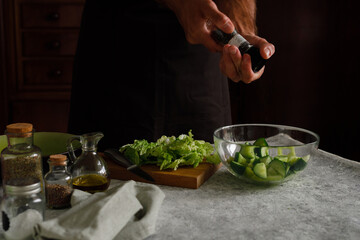 a man is preparing a vegetable salad. Adds spices