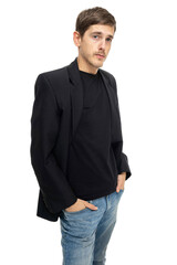 Young handsome tall slim white man with brown hair with hands in pockets in black blazer in blue jeans isolated on white background