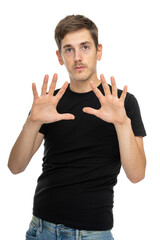 Fototapeta premium Young handsome tall slim white man with brown hair showing his palms in black shirt in blue jeans isolated on white background