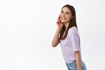 Image of beautiful girl touch her natural no make up face, smiling pleased, smooth and clean skin after cleansing beauty products, advertisement concept, white background