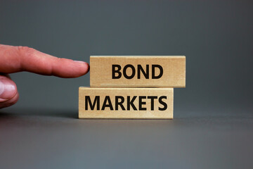Bond markets symbol. Wooden blocks with words 'Bond markets' on beautiful grey background, copy space. Businessman hand. Business and bond markets concept.