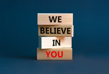 We believe in you symbol. Concept words 'We believe in you' on wooden blocks on a beautiful grey background. Businessman hand. Business, religion and we believe in you concept.