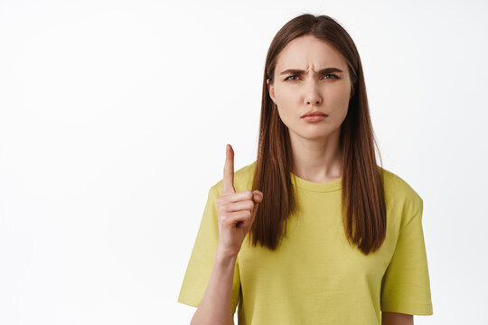 Close Up Of Girl Makes Confused Face, Dont Get It, Pointing Up, Frowning And Squinting Puzzled, Cant Understand Smth, Standing Against White Background