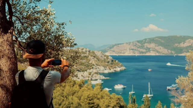 Man Using Mobile Phone For Selfie Photo.Selfie On Smartphone In Beautiful Place.Attractive Tanned Man Sunbathing Using Mobile App For Photo Video.Guy Taking Picture On Vacation Holiday Mediterranean
