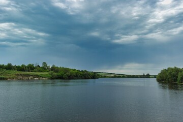 Summer landscape on a riverside flooded meadow with trees and lush green grass