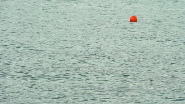 Orange buoy on the water. Ripples in the water. Water markings. Restriction of movement. Buoy pointer. Signal float.