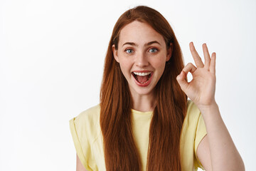 Awesome, very good. Smiling ginger girl shows okay no problem gesture, praise and compliment...