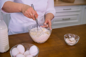 woman's hands prepare food, whisk the dough with a whisk, baking, close-up

