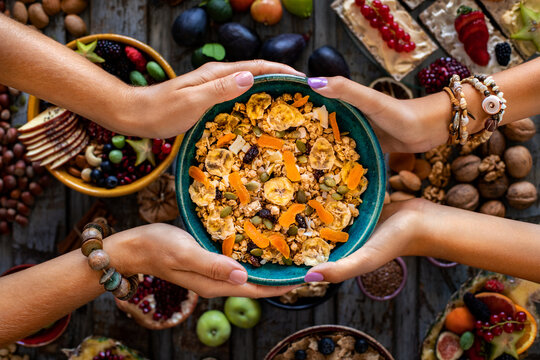 Hands of two women sharing their breakfast bowl. Breakfast with fresh fruit and muesli.