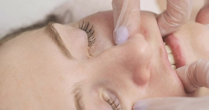 Girl in massage room at facebuilding session. Young woman receiving facial massage. Close up