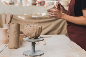 close up view of handmade clay pot near blurred young african american woman on foreground in pottery