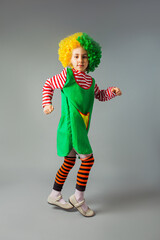 The little girl jumps in a clown uniform