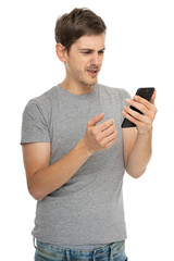 Young handsome tall slim white man with brown hair looks disappointed in gray shirt with mobile phone isolated on white background