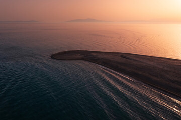 Fototapeta na wymiar Aerial view to a long narrow sandy beach stretched into the sea in sunset tints