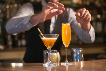 Bartender stirring, squeezing lemon/lime and preparing cocktails and alcoholic beverages in...