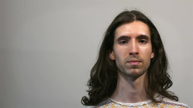 Young long-haired man touching, messing his hair