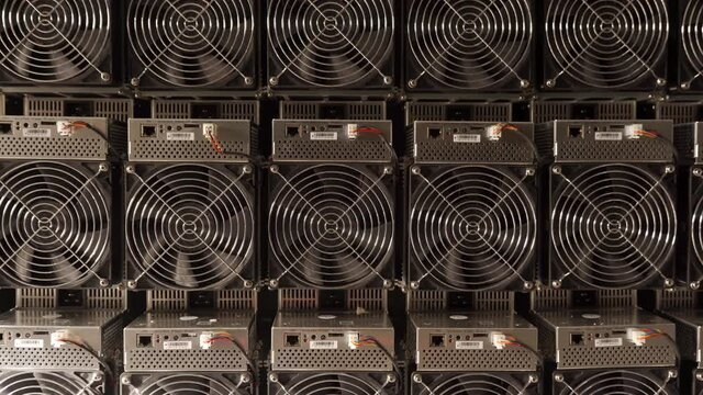 Bitcoin ASIC miners in warehouse. ASIC mining equipment on stand racks for mining cryptocurrency in steel container. Fan grills and ventilators for cooling electronics. Air coolers.