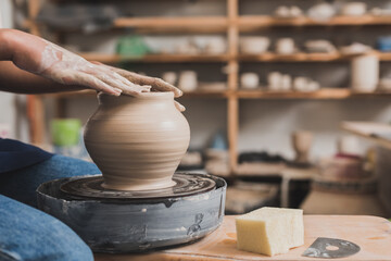 close up view of young african american woman working with wet clay pot on wheel in pottery
