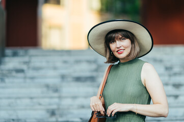 Woman with sunglasses and hat walking in the city
