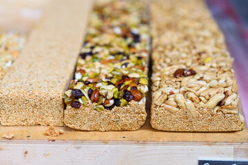 Sweet halva, dessert from sesame seeds with nuts on the board in the market. Selective focus.
