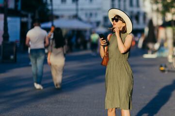 Woman with phone and hat walking in the city