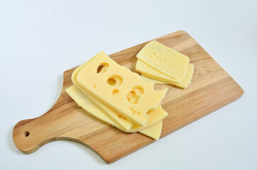 Slices of Emmental cheese and Tilsit cheese on cutting board