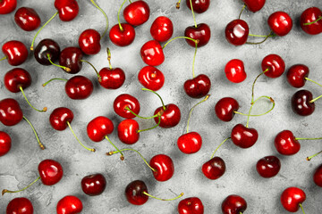 Fresh cherries are scattered on a gray background.