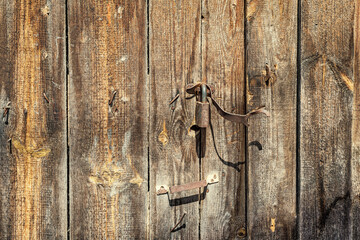 An old wooden gate with a rusty lock, background.