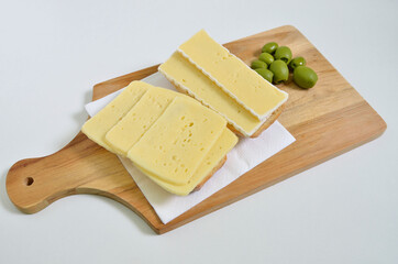 Two Cheese sandwiches on Cutting board with green Olives