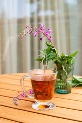 Fireweed herbal tea in the glass cup on wooden table