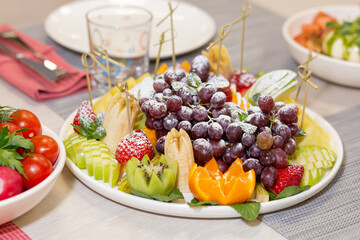 Raw fruits berries platter, oranges, kiwi strawberries, blueberries grapefruit grapes, apples on the white plate, top view, selective focus